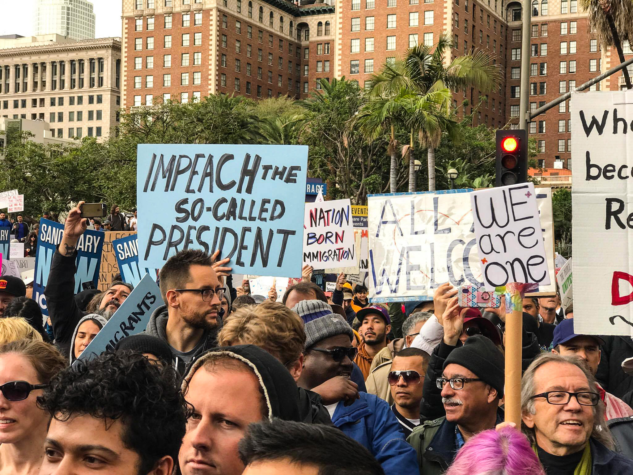 Protesters hold signs reading "impeach Donal Trump"