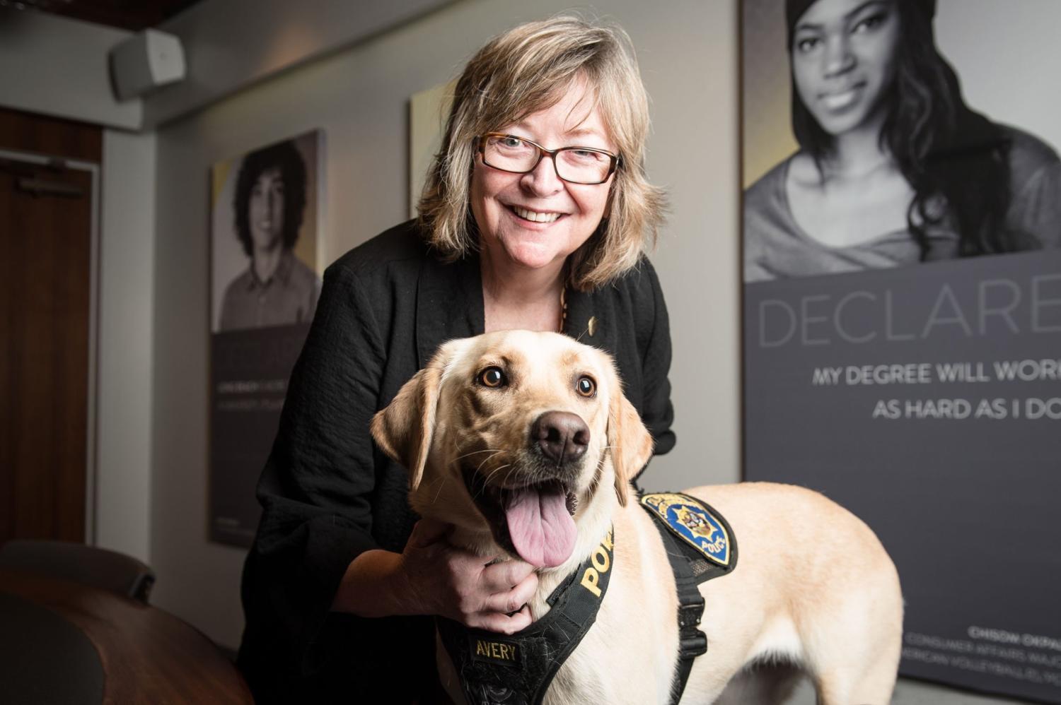 President Jane Close Conoley gives new bomb-sniffing dog, Avery, a hug.