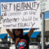 A woman holds a sign reading "all content on the internet should be treated equally" 12/7.