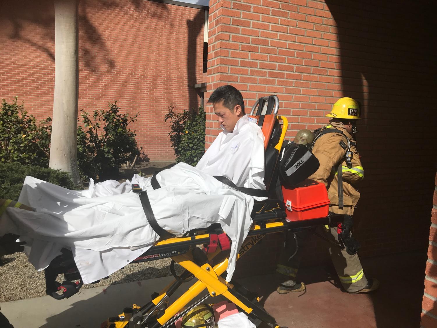 Assistant Professor of Chemical Engineering Ted Yu is wheeled out on a stretcher after sustaining injuries during a fire. Two engineering buildings were evacuated Tuesday after a chemical reaction sparked a fire in the Engineering and Computer Sciences building.