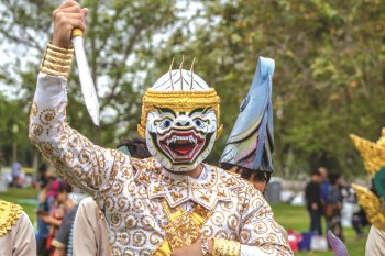 A person wearing a white mask holds a toy blade in a dance.