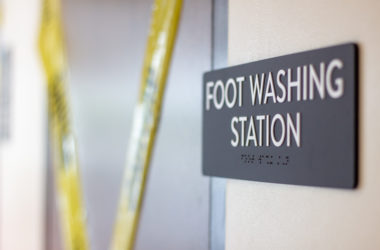 A sign that reads "Foot Washing Station," behind is a door cordoned off by caution tape