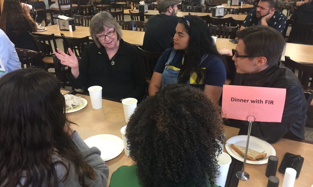President Jane Close Conoley sits with dorming residents in dining hall