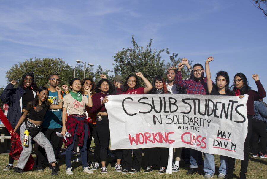 Demonstrators hold up a sign that says "CSULB students in solidarity with the working class"