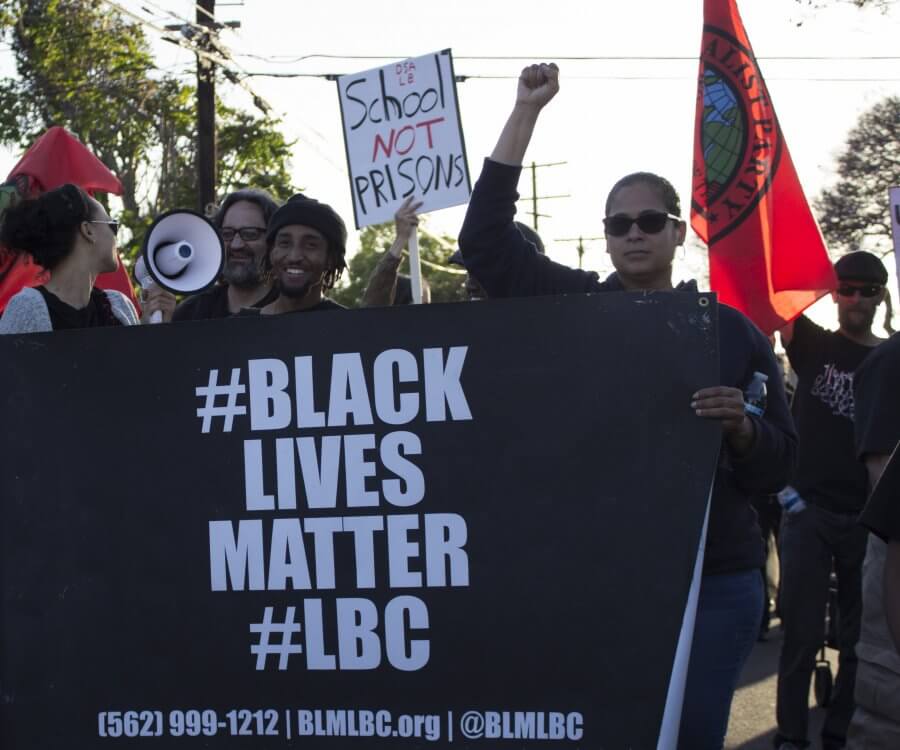Protestors hold a sign that reads "#Black Lives Matter #LBC"