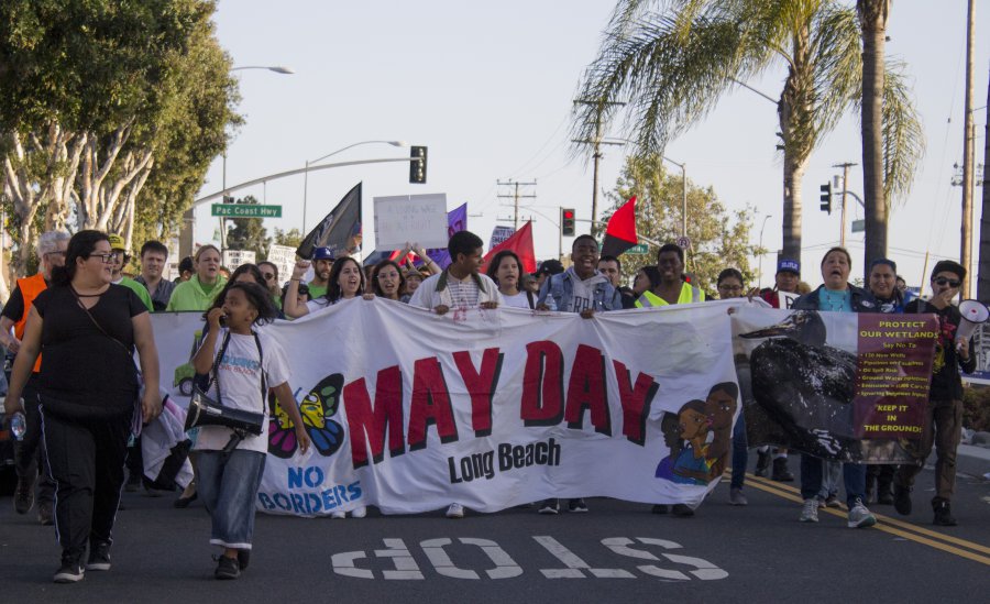 Protestors hold up a sign that says May Day