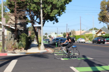 A woman rides through a green protected bike lane.