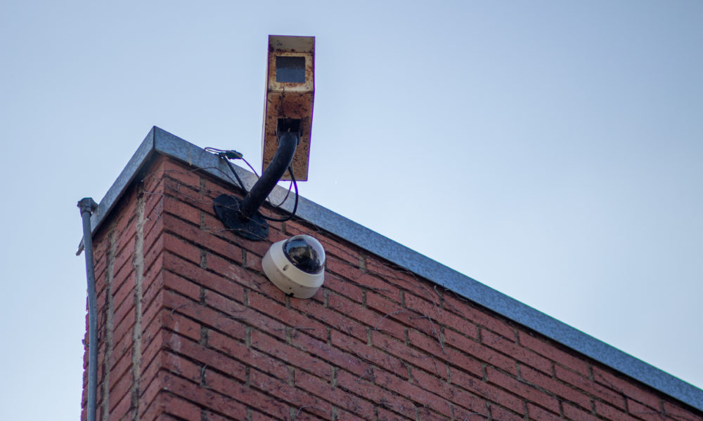 A old and rusted security camera hangs over a newer model security camera.