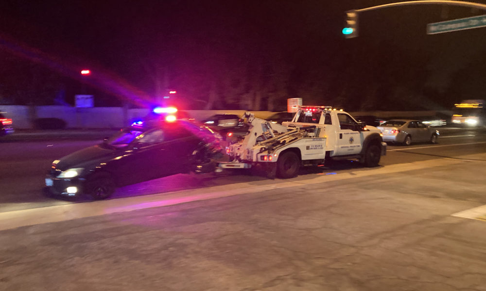 A damaged vehicle being towed away from the scene of an accident
