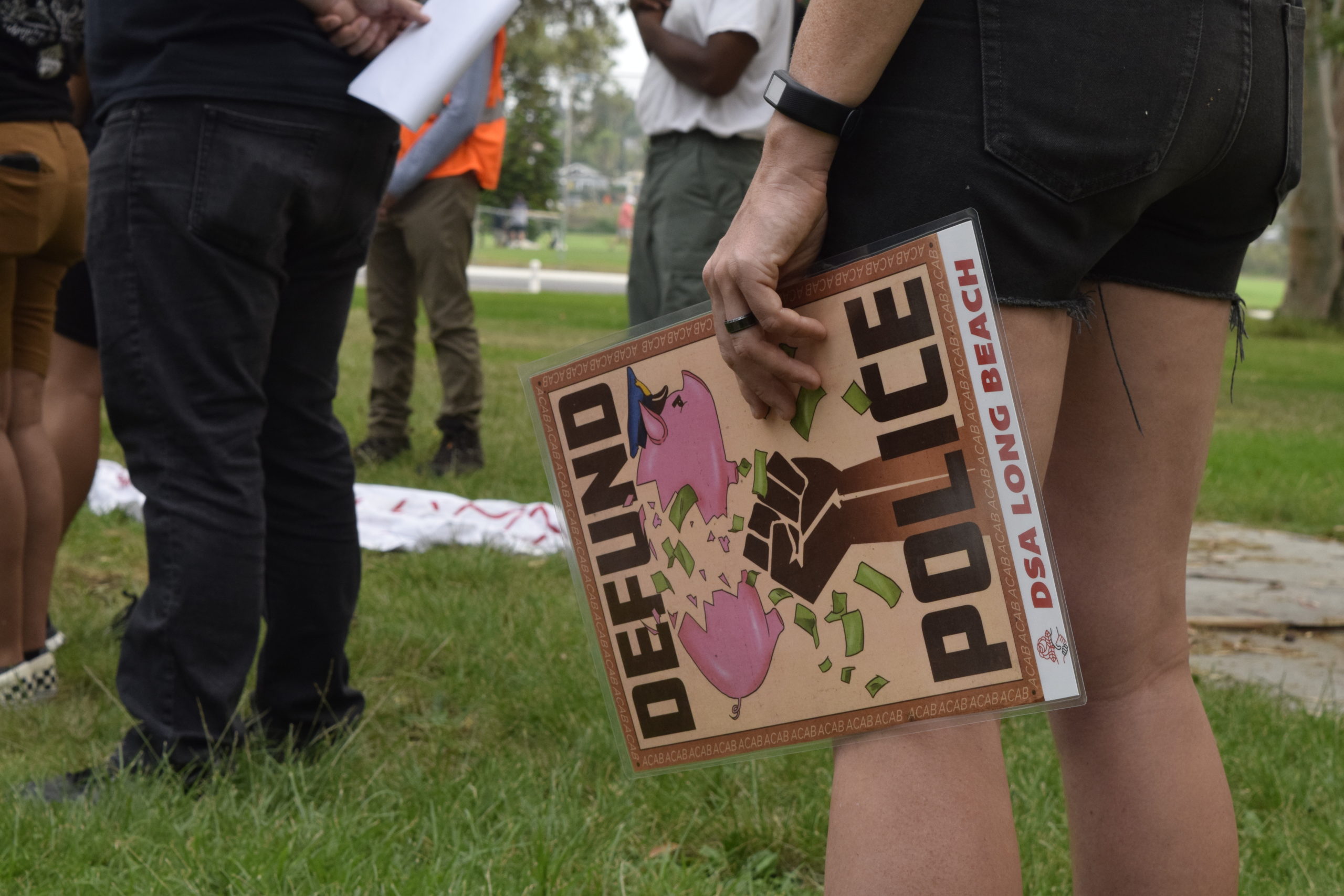 A protester holding a sign that reads "Defund the Police"