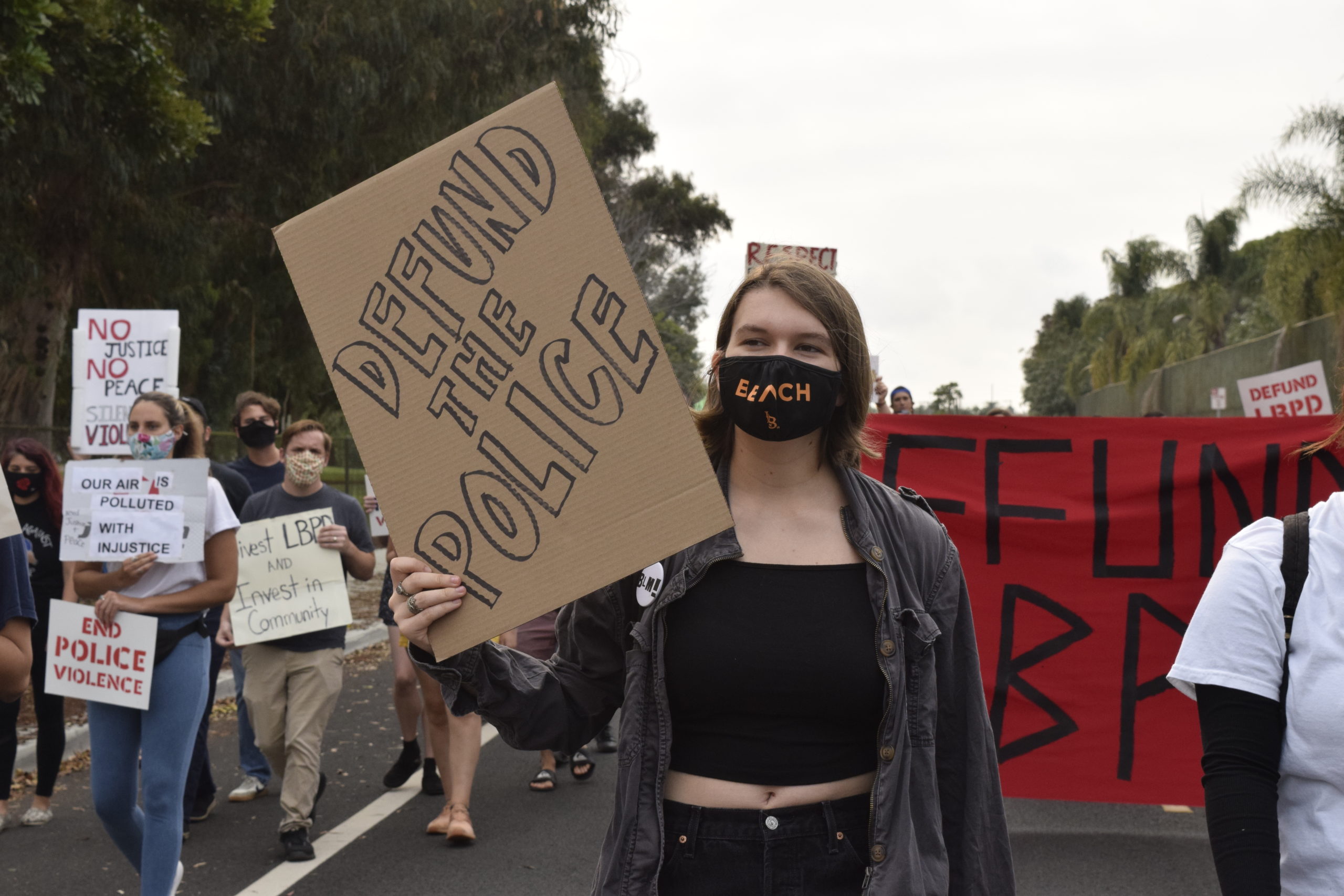 A girl marches with a sign that reads "defund the police"