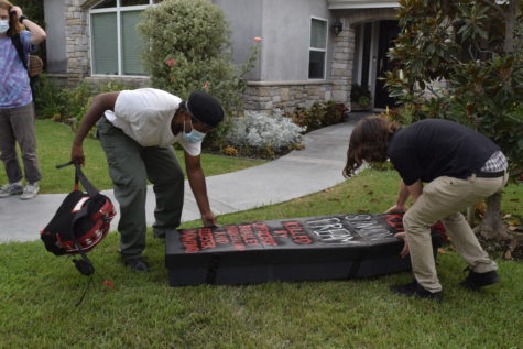 Two men lay a mock coffin on the ground