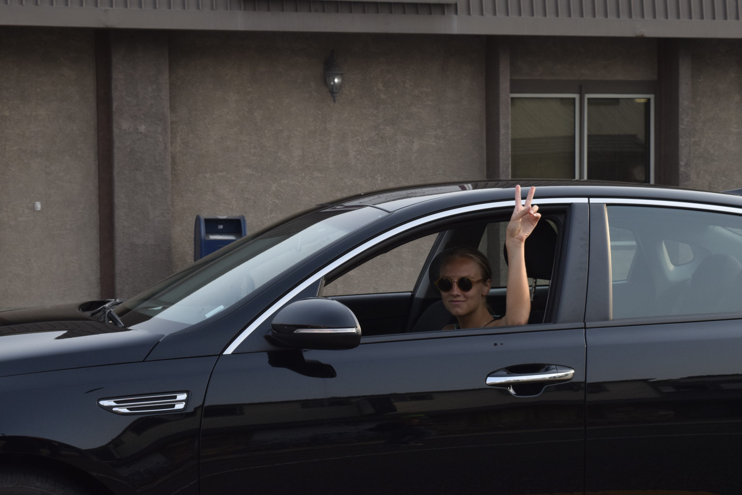 A woman driving by flashes a peace sign