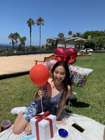 A girl sits by the beach with birthday balloons