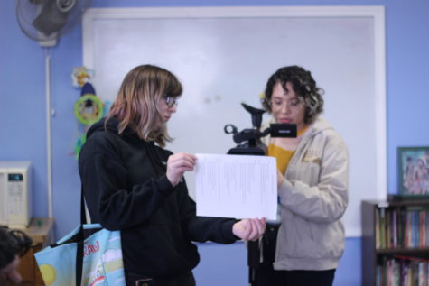 Two women with a camera look at a script