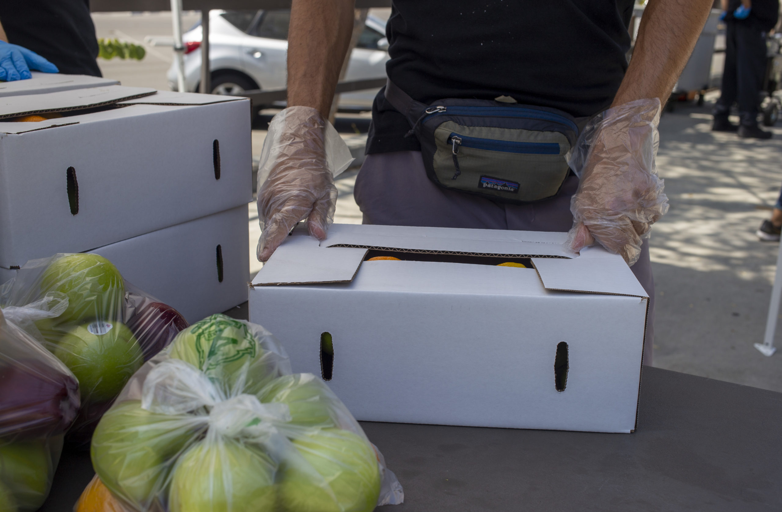 A volunteer packages food into a white box