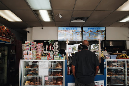 Inside of Simone's Donuts a man orders at the counter which is protected by a plastic shield due to COVID-19