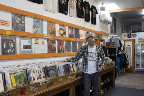 Gary Farley, owner of Third Eye Record Store poses in front of collected records and graphic t-shirts.
