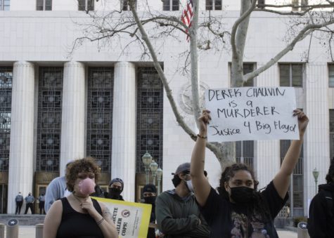 people hold signs in front of a building in Los Angeles