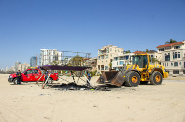 Beach maintenance crew members clean up debris from the site where the rainbow lifeguard tower had burnt down on March 23, 2021. Photo by Peter Villafane.