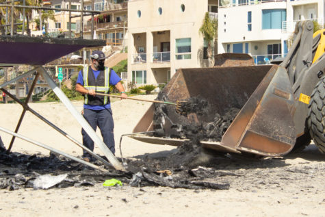 A beach maintenance crew member shovels debris from the site where the rainbow lifeguard tower had burnt down on March 23, 2021. Photo by Peter Villafane.