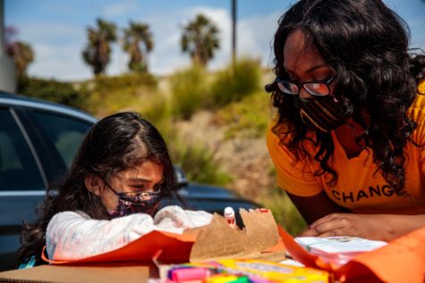 Chynna Bryson helps Luna Estrada, age 6, to color her sign for the protest.