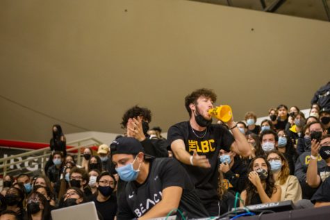 DJ Cast plays some music while students cheer on behind him