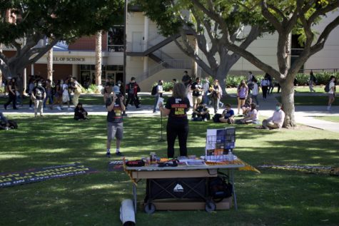 Several CSULB students listen to Revcom supporters advocate for equality and pro-choice through a revolution to "overthrow the capitalist-imperialist system" of government.