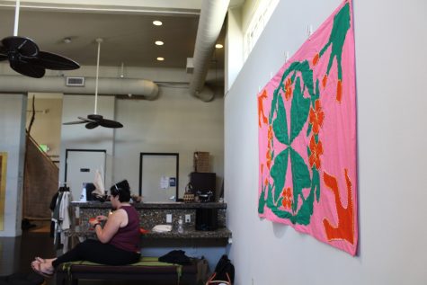 Pasifika artist Melodie Bergquist-Turori embroidering next to their tivaevae art installation.