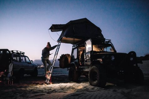 A camper setting up a tent on top of their car on Pismo State Beach