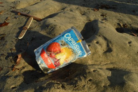 A Caprisun and a nail file littered at the beach.