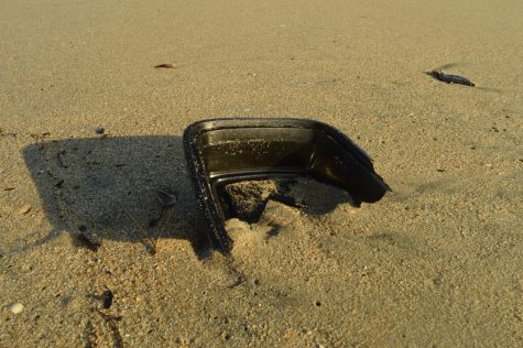 Broken plastic Tupperware in the sand.