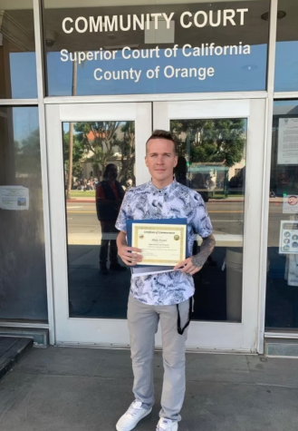 Krawl in front of the Community Court of Orange County holding a graduation certificate for opportunity court