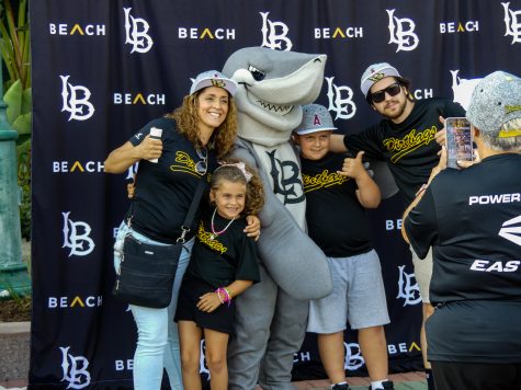 Elbee the shark posing for students and alumni family photos accompanied by ASI and assorted student media representatives.