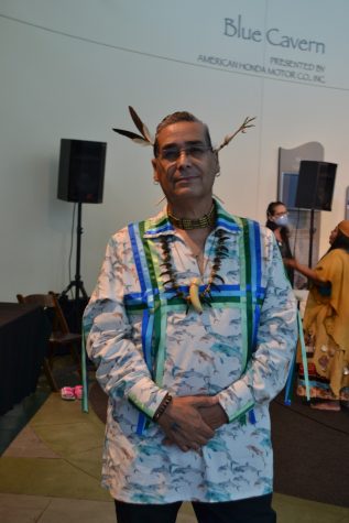 Emcee Christopher Tādai Diaz of the Tongva Nation poses after a Chumash Family Singers performance. He wears a traditional choker and a feather headwear.