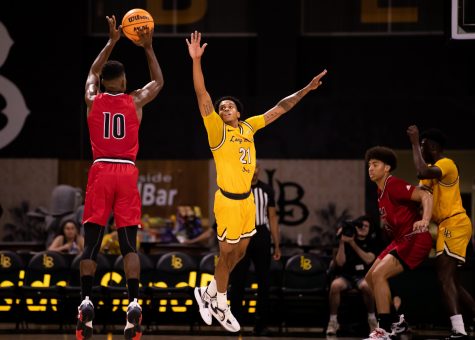 LBSU sophomore guard Tone Hunter leaps to contest the long-range two point shot from Biola redshirt senior guard Alex Wright during The Beach's win at home on Friday.