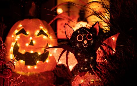 10/27/2022: Long Beach, CA- As the sun is set and the moon rises, the lights in front of homes light up the street. A decorative sweet looking bat spreads its wings while next to a smiling pumpkin on Coronado Avenue Thursday night.