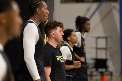 Long Beach State Men's basketball graduate assistant coach, Micguire Monson, watches on as his father, head coach Dan Monson, leads the practice and introduces the next drill.
