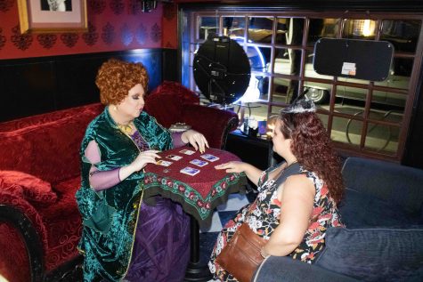 Madame Ozma (left) dressed as Winifred Sanderson, a witch in the Disney film "Hocus Pocus," performing a Tarot reading for Tarah Daniels.