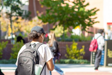 A student wears earbuds while passing the Student Success Center.