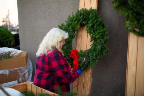 Cindy decorates wreaths with ribbons, pinecones, and other decor to prepare them for sale.