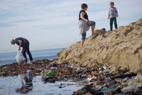 Jackie Lean and her family clean Seal Beach after high tides wash garbage and plastic along the shore Saturday morning.