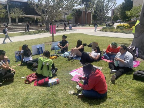 Members Let '23 Walk lounge on the quad grass as they continue to protest the university's decision to hold their commencement at Angel Stadium