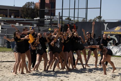 04/06/2023 - Long Beach, Calif: LBSU Beach Volleyball team doing the wave to energize their teammates for the very last match of the day.