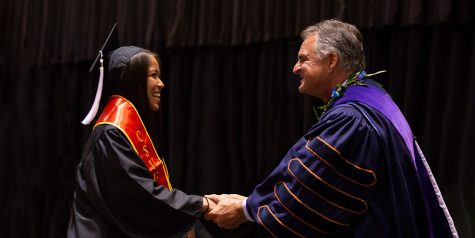 President Framroze Virjee shakes and congratulates a CSUF student's hand at commencement