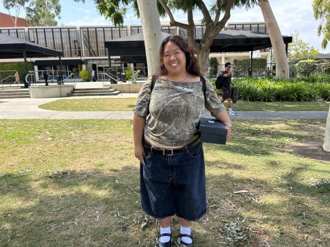 First-year fashion merchandising student Claire Nguyen styles an off the shoulder camo t-shirt, dark wash jorts and an assortment of silver jewelry.