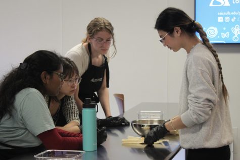 10/12/2023 - Long Beach, Calif: ASI Beach Kitchen volunteer Shane Silva teaches students how to begin preparing tamales during a cooking class on Thursday.