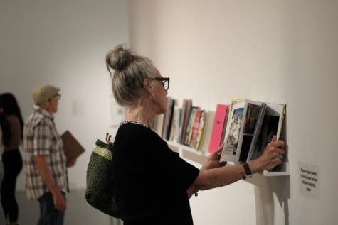 10/3/2023 - Long Beach, Calif: One of many attendees look intently at the books on the shelves, just before the Artist Talk took place. This was one of many mediums shown off as there was video of artist Pau Pescador, some of Pescador’s books and art work.